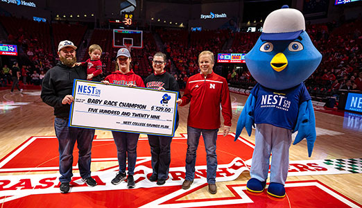 Nester at a Nebraska Cornhuskers basketball game with winners of a previous Baby Crawl contest.